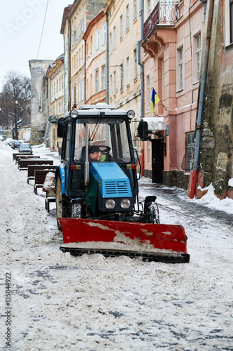 small tractor cleans the town's narrow streets from snow