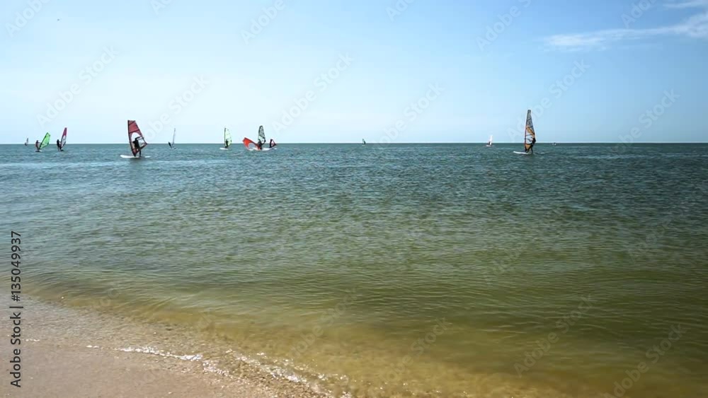 Wind-surfing. Dark silhouettes of surfers riding on sailboards on the sea waves at sunny day. HD Wind-surfing. Dark silhouettes of surfers riding on sailboards on the sea waves at sunny day. HD
