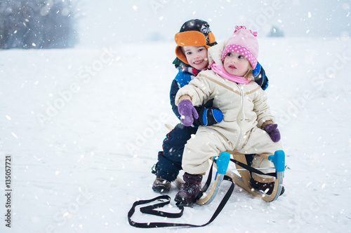 Little girl and boy enjoy a sleigh ride. Children sledding outdoors.