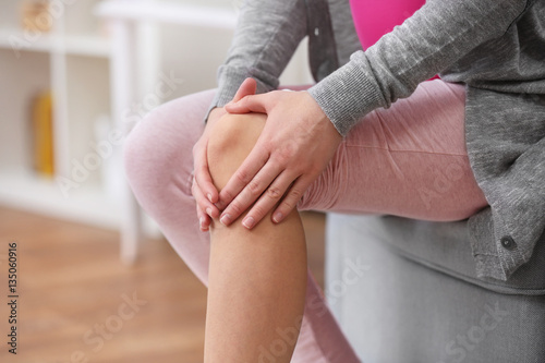 Young woman suffering from pain in knee, close up photo