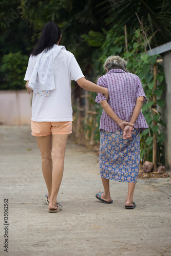 Asian senior mother and adult daughter holding hands walking at