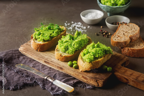 Baguette with mashed green peas and mint. Dark background. Selec