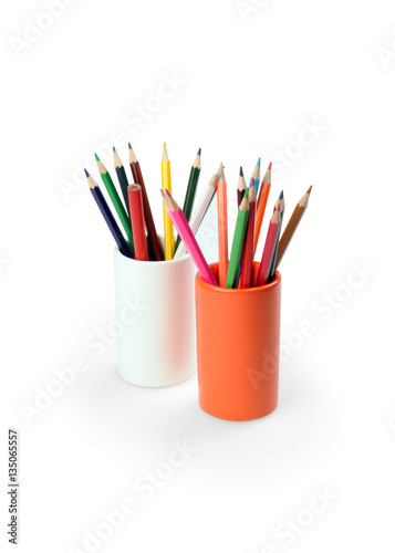 colorful pencils in an orange glass ceramic. on a white background