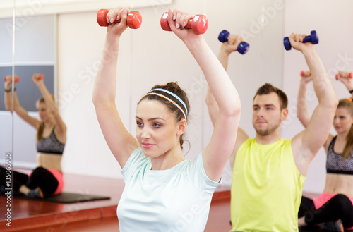 Young people working out with dumbbells in gym