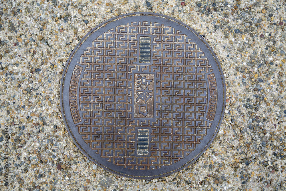 Circle steel manhole cover or metal sewer on the street in Japan