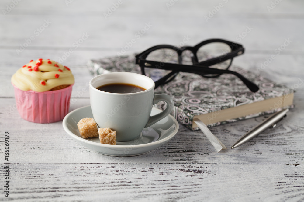 Cup of coffee and muffin on office table in begining of working