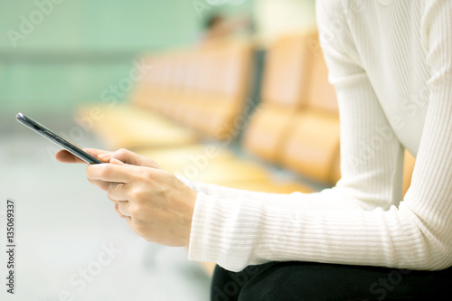 Woman at airport texting on a smartphone