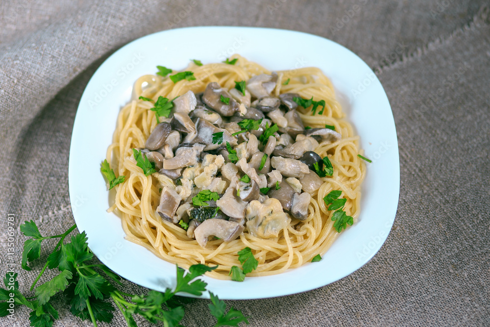 mushrooms of a veshanka and champignons in sauce with macaroni in a white plate on a table mushrooms of a veshanka and champignons in sauce with macaroni in a white plate on a table