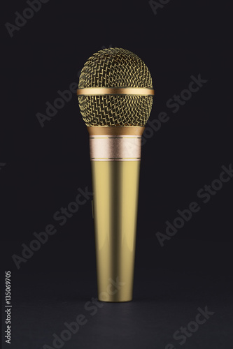 A gold wireless microphone on a black background