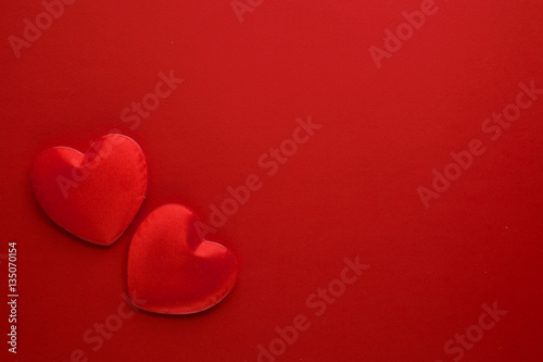 Two decorative hearts are on red paper. Flat lay.