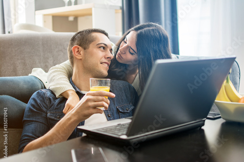 Cheerful couple using laptop at home.
