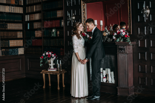cute wedding couple in the interior of a classic studio . hey kiss and hug each other, holding hands looking at each other