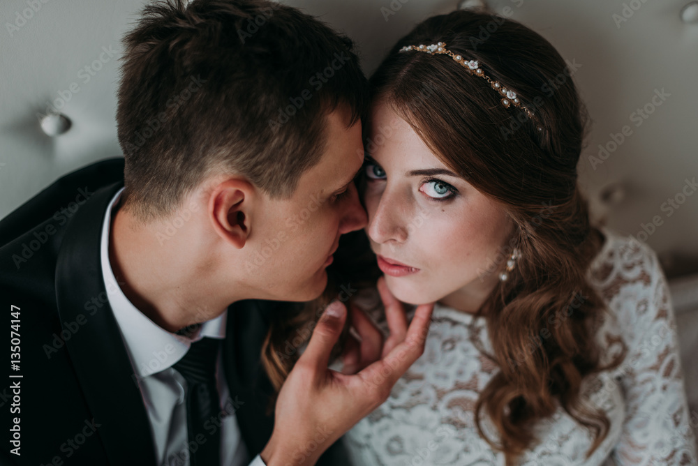 cute wedding couple in the interior of a classic white studio decorated. hey kiss and hug each other, holding hands looking at each other cute wedding couple in the interior of a classic white studio decorated. hey kiss and hug each other, holding hands looking at each other