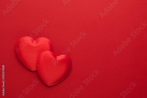 Two decorative hearts are on red paper. Flat lay.