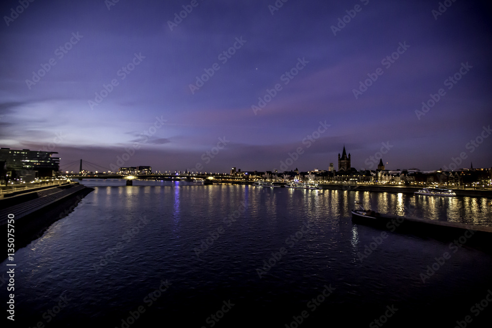 Blick auf den Rhein von einer Brücke in Köln in der blauen Stunde