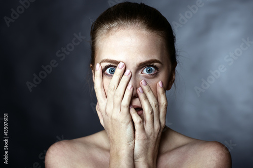 Scared girl covering her face with her hands