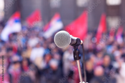 Protest. Public demonstration. Microphone in focus, blurred crowd in background.