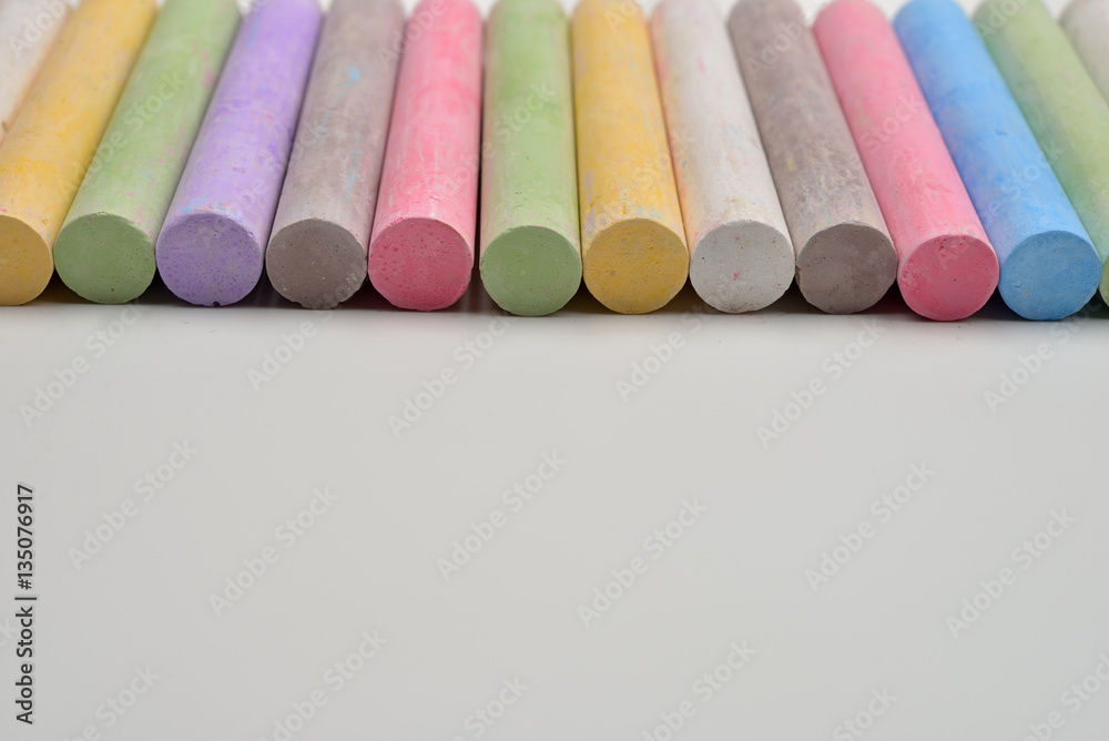 Pieces of chalks in a variety of colors arranged in line on a wh Pieces of chalks in a variety of colors arranged in line on a wh