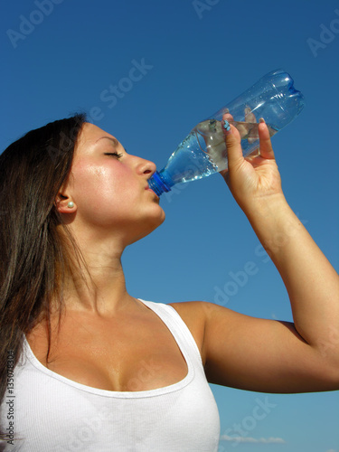 young athletic woman drinks cold water in hot day, vertical composition