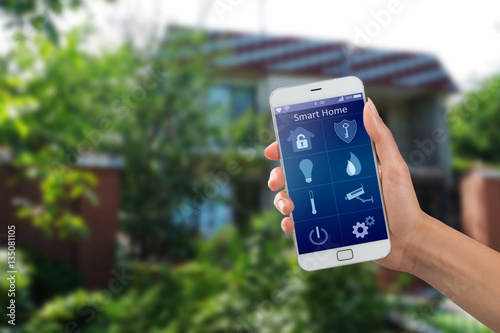 Smartphone with home security app in a hand on the building background