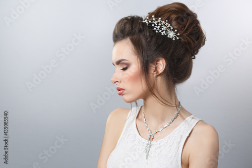 Beauty portrait of an elegant bride with a beautiful hairstyle and make-up, isolated on a gray background.