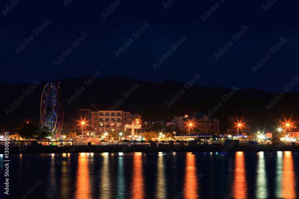 Ferris wheel in the motion at the night city beach. Lermontovo, Russia