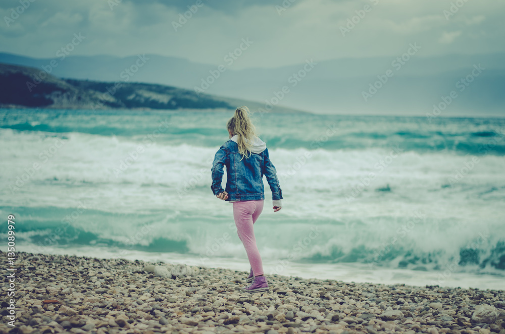 lonely girl walking by the sea in bad weather