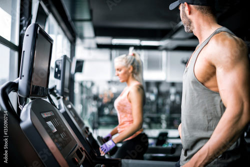 Attractive man running on treadmill and looking at girl