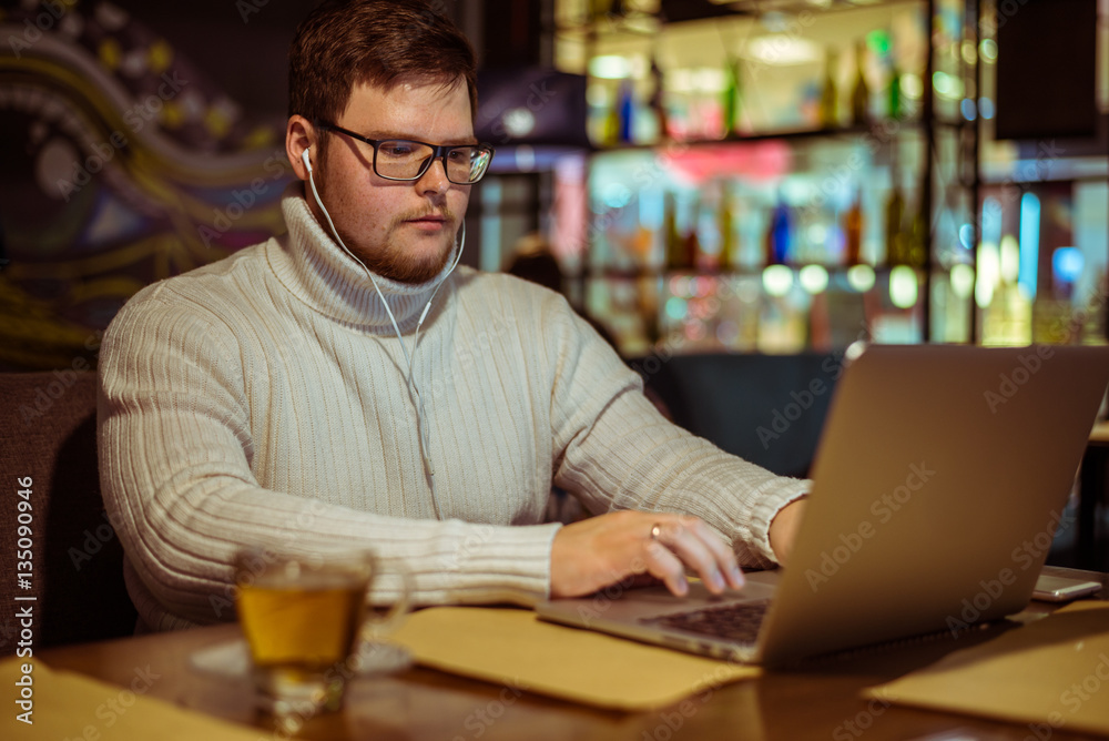 Handsome young man with laptop and cup in a cafe Handsome young man with laptop and cup in a cafe