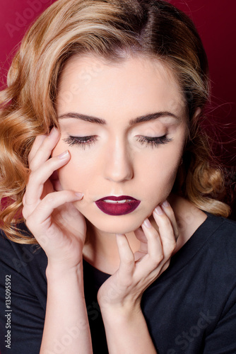 beautiful girl in a black dress on a red background with red lips sitting on a red chair