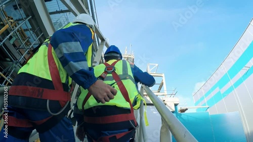 Engineer and worker climbing the tower of a large oil refinery photo