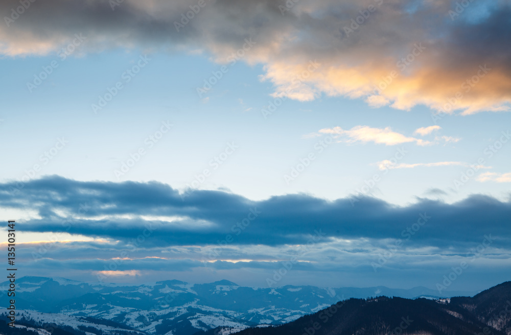 Beautiful winter mountain landscape at sunset with blue sky and dramatic clouds