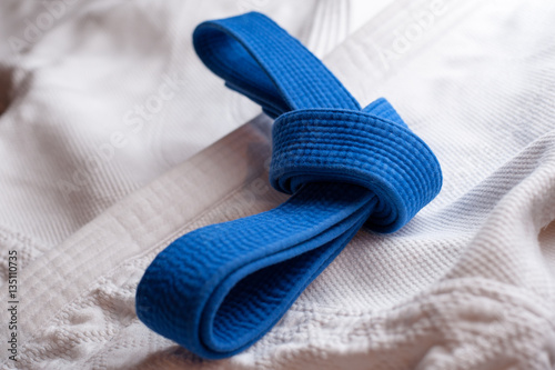 Blue martial arts belt tied in a knot with white kimono in background