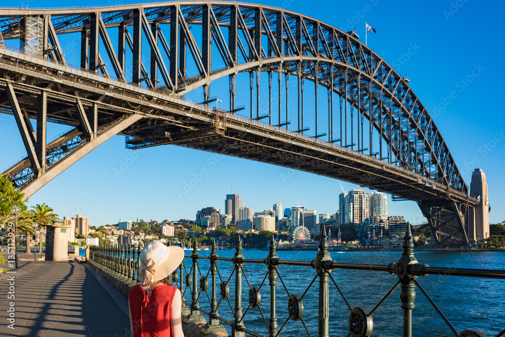 Fototapeta premium Woman in bright top and hat against Sydney Harbour Bridge on the