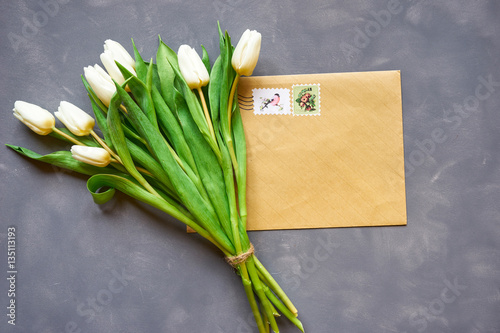 White tulips bouquet and postcard on grey background