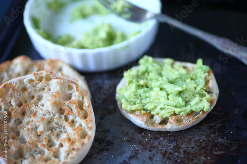 English muffins with avocado toast on old metal surface
