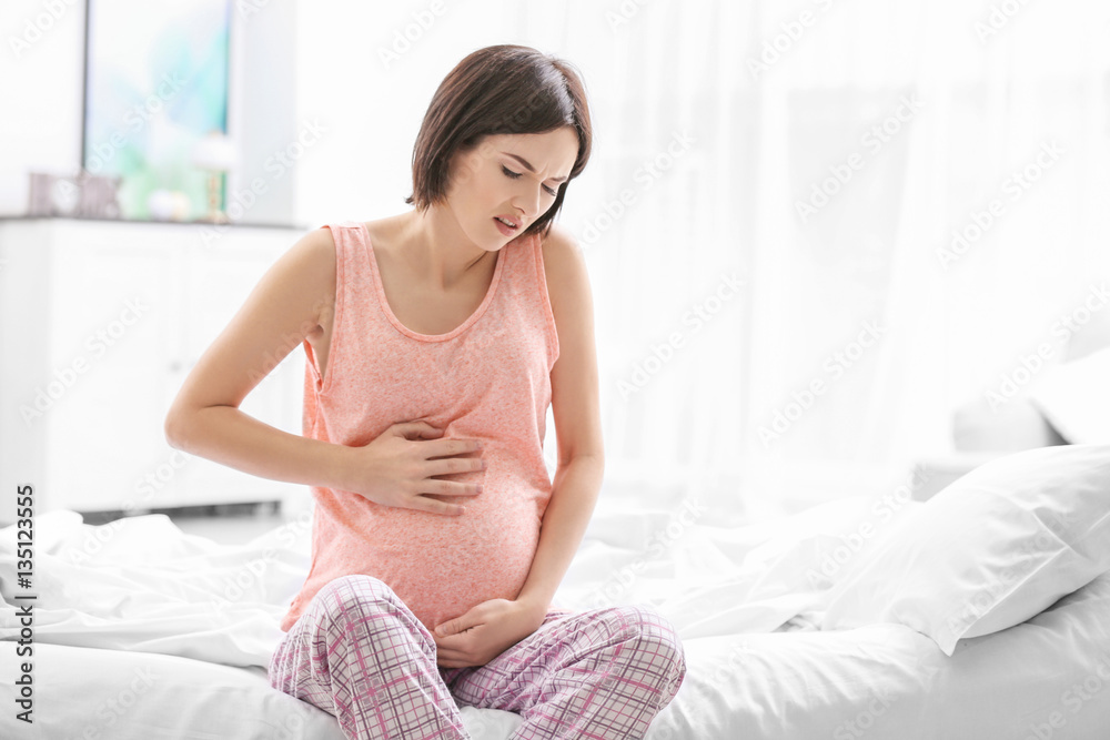 Young pregnant woman suffering from abdominal pain at home Young pregnant woman suffering from abdominal pain at home