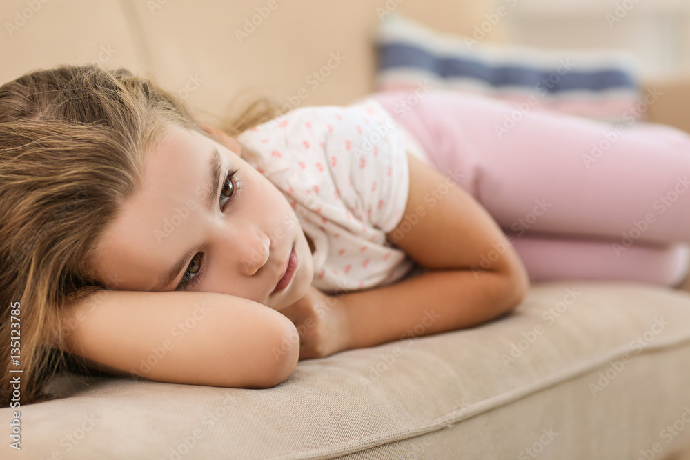 Sad little girl lying on sofa, closeup
