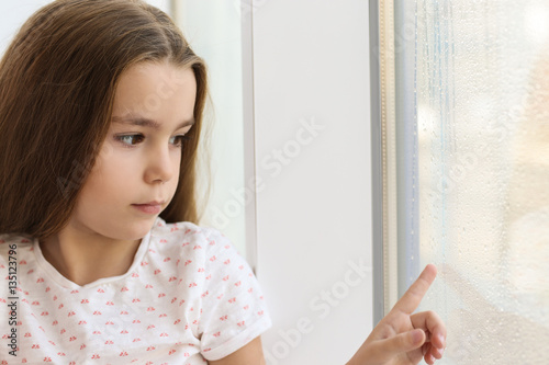 Sad little girl drawing on ...