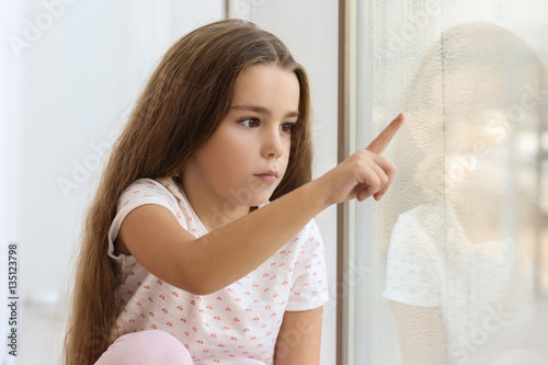 Sad little girl drawing on ...