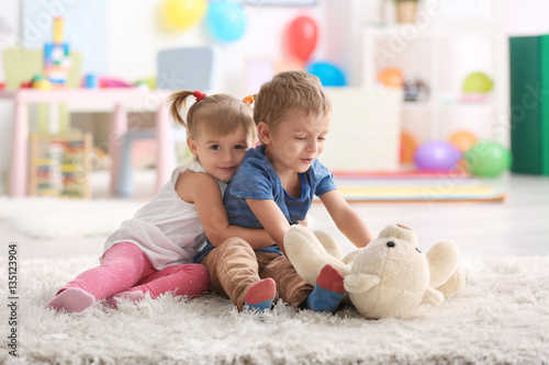 Cute funny children playing with teddy bear at home
