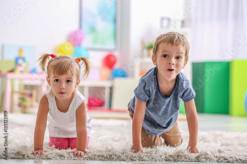 Cute funny children playing on carpet at home