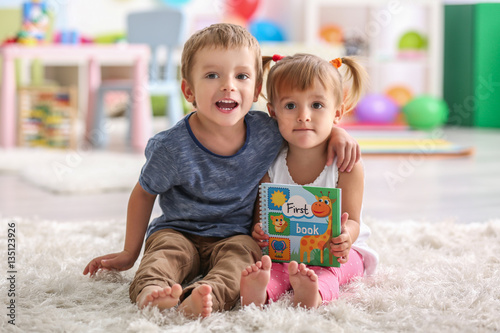 Cute funny children sitting on carpet with book