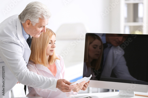Doctors working at table with computer in clinic