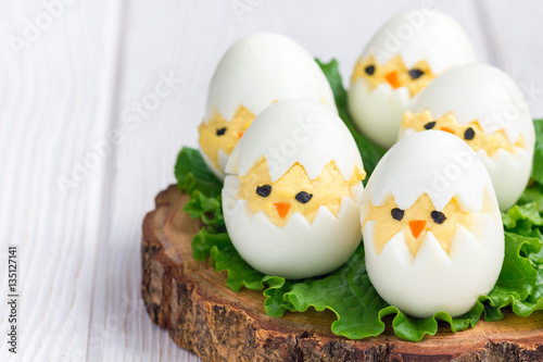 Little chicken in nest, deviled eggs served with salad on wooden board, horizontal, copy space