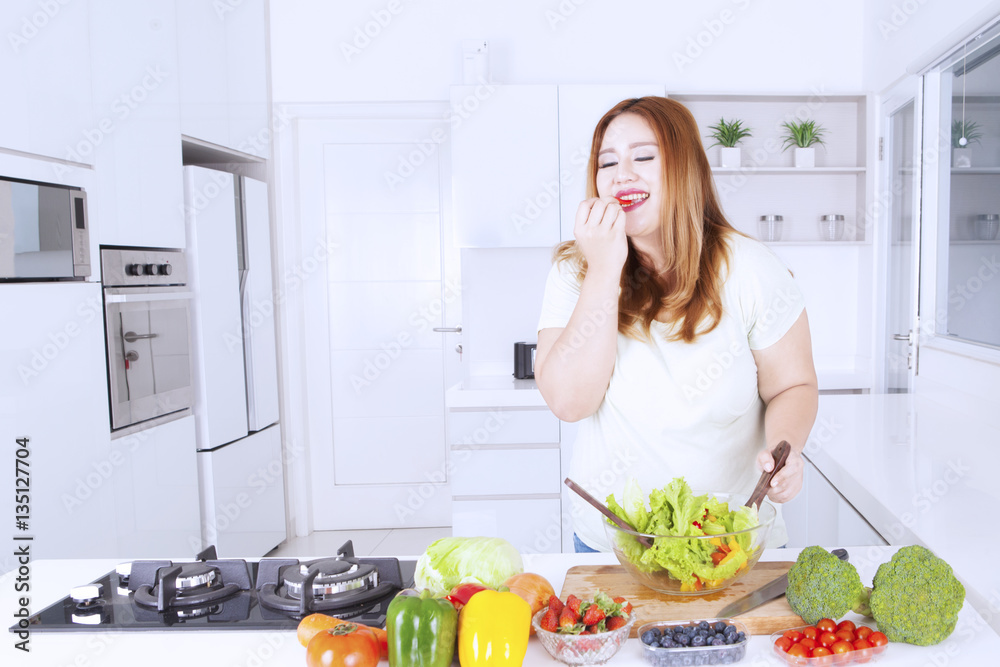 Fat woman tasting salad on the kitchen Fat woman tasting salad on the kitchen
