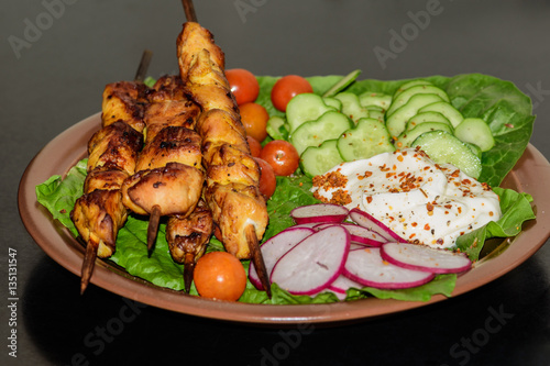 Chicken kebabs with vegetables on a clay plate