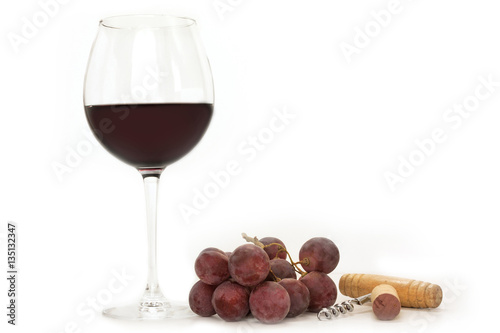 Glass of red wine with grapes, cork, and corkscrew