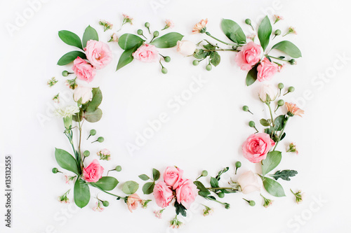 Round frame made of pink and beige roses, green leaves, branches on white background. Flat lay, top view. Valentine's background