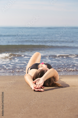 Young beautiful tanned woman laying on sea beach